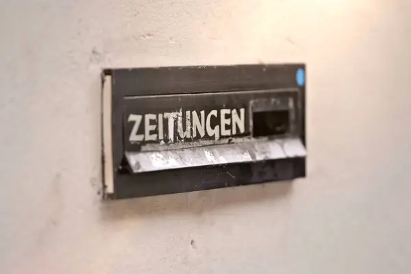 Close-up of mail slot with text Zeitungen (German, translation is newspapers) . Horizontal image with selective focus.