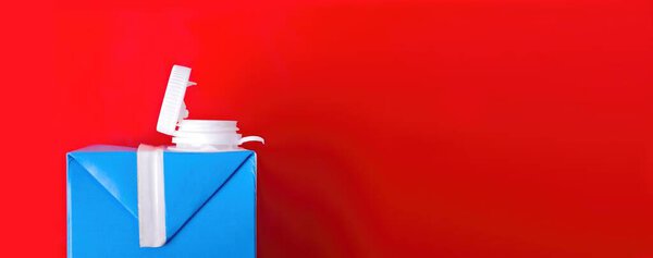 Milk carton box on red background with copy space.. Recycling concept.