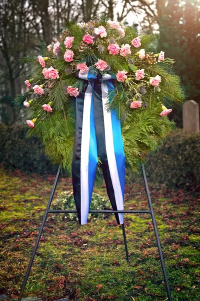 Pink funeral flower wreath on the cemetery. Vertical image with selective focus.
