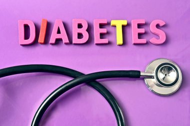 Mor arka planda steteskopun yanında renkli kelime Diyabet.