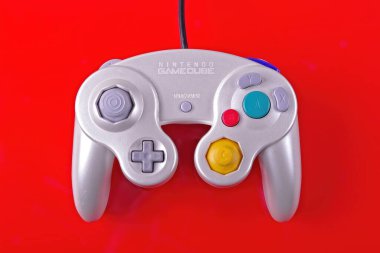 Neu-Ulm, bavyera, Almanya - 26 Ağustos 2024: Nintendo Gamecube oyun denetleyici kırmızı arkaplanda izole edildi.