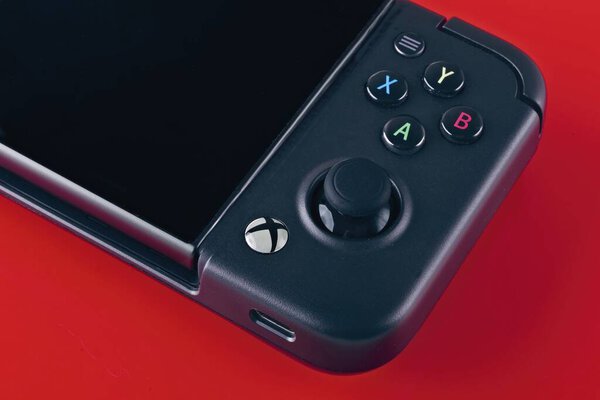 Neu-Ulm, Germany - July, 02, 2025: Close-up of Xbox handheld controller by Gamesir. on red background.