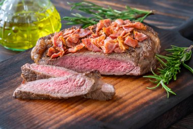 Sliced beef steak with crumbled bacon garnished with rosemary