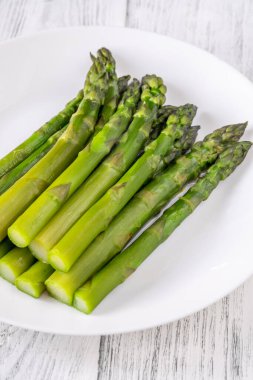 Beyaz arka planda bir sürü haşlanmış kuşkonmaz.