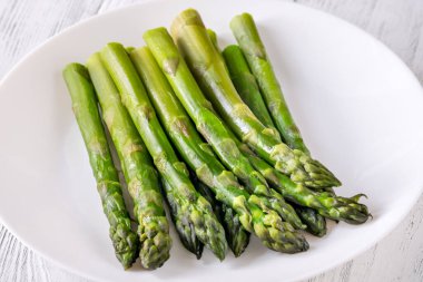 Beyaz arka planda bir sürü haşlanmış kuşkonmaz.