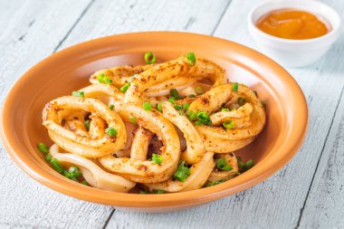 Ahşap masada bir kase kızarmış kalamar halkası.