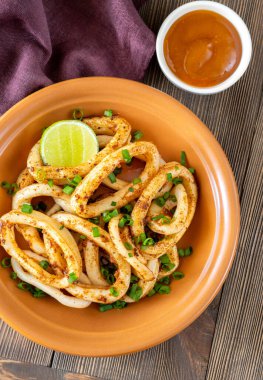 Ahşap masada bir kase kızarmış kalamar halkası.