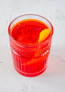 Portakal kabuğuyla süslenmiş bir bardak Negroni kokteyli.