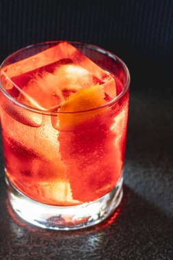 Portakal kabuğuyla süslenmiş bir bardak Negroni kokteyli.