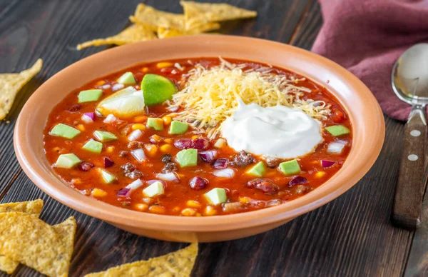 Bowl of taco soup garnished with cheese and sour cream