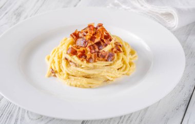 Kızarmış guanciale ile süslenmiş bir porsiyon Carbonara makarna.