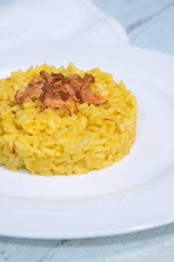 Pancetta ile süslenmiş safran risotto porsiyonu.