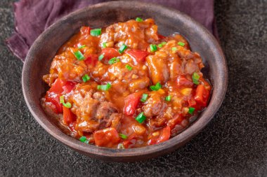 Siyah arka planda bir kase tavuk mançuryası.