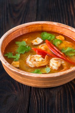 Ahşap zemin üzerinde bir kase Tom yum çorbası.
