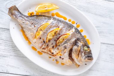 Limon ve kırmızı yağla süslenmiş fırında Dorado balığı.