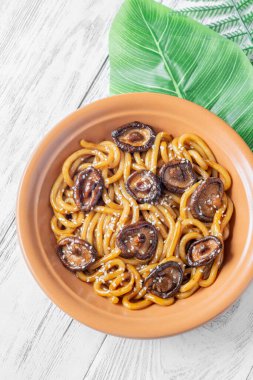 A portion of udon noodles with soy unagi mirin ginger sauce, shiitake and enoki mushrooms, and green onion clipart