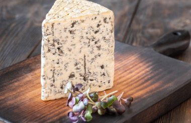 Kremalı, damarlı rokfor peyniri, kalın aromalı, ahşap bir tahtanın üzerine zarif bir şekilde yerleştirilmiş.