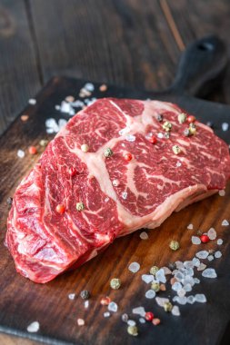 Koyu, mermer pirzola bifteği, tuzlu ve biberli, köy tahtasında dinleniyor.