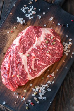 Koyu, mermer pirzola bifteği, tuzlu ve biberli, köy tahtasında dinleniyor.