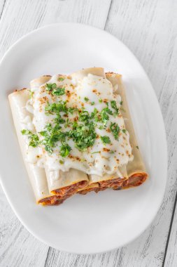 Erimiş mozzarella battaniyesinin altında pişirilmiş bol bol bolonez sosuyla dolu nefis cannelloni makarnası.