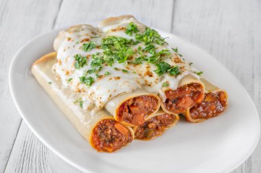 Erimiş mozzarella battaniyesinin altında pişirilmiş bol bol bolonez sosuyla dolu nefis cannelloni makarnası.