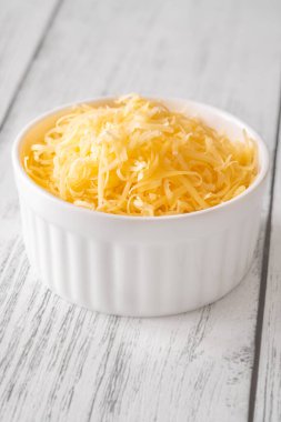 Beyaz kasede parlak rendelenmiş çedar peyniri, eritmek ya da tepelemek için mükemmel.