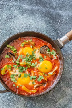 Baharatlı domates soslu yumurta, mantar, biber ve taze otlar.