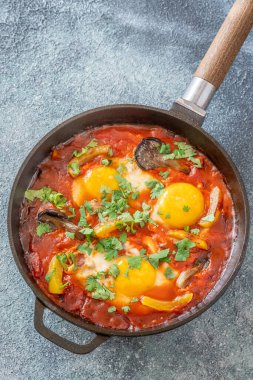 Baharatlı domates soslu yumurta, mantar, biber ve taze otlar.