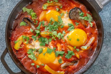 Baharatlı domates soslu yumurta, mantar, biber ve taze otlar.