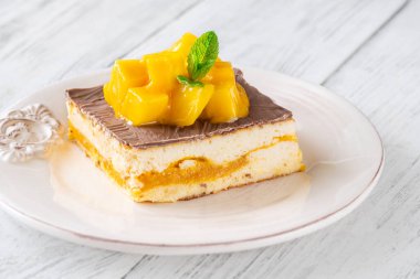 Taze mangoyla taçlandırılmış, mango hamurlu ve çikolata jöleli nefis peynirli kek.