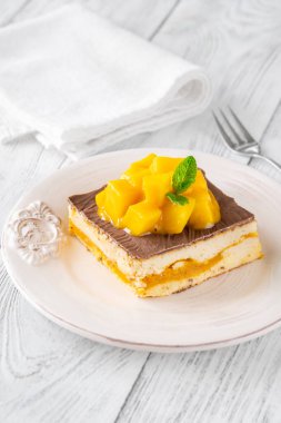 Taze mangoyla taçlandırılmış, mango hamurlu ve çikolata jöleli nefis peynirli kek.