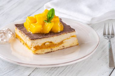 Taze mangoyla taçlandırılmış, mango hamurlu ve çikolata jöleli nefis peynirli kek.