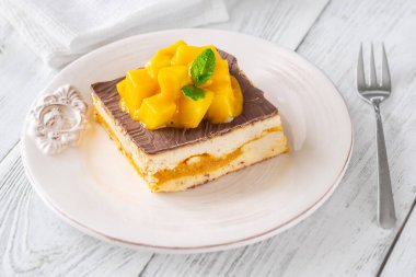 Taze mangoyla taçlandırılmış, mango hamurlu ve çikolata jöleli nefis peynirli kek.