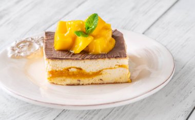 Taze mangoyla taçlandırılmış, mango hamurlu ve çikolata jöleli nefis peynirli kek.