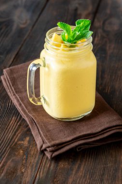 Altın mango lasi kavanozda parlıyor, taze nane ve mango küpleri güzelce süsleniyor.