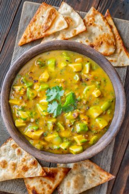 Üçgen tortilla cipsi. Mango, avokado, kişniş ve kırmızı soğanlı salsa sosu.