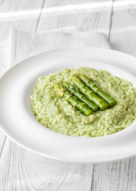 Yeşil kuşkonmaz uçlu kremalı risotto, süslenmiş ve güzelce sunulmuş.