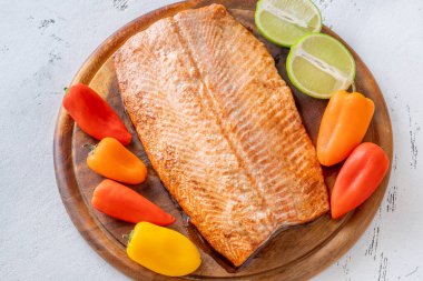 Parlak sebzeler pişmiş somon filetosunu sarıp ahşap mutfak düzenine tazelik katıyor.