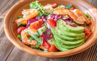 Canlı salata karidesleri avokado taze yeşiller narenciye soslu ahşap masa kırsalları.