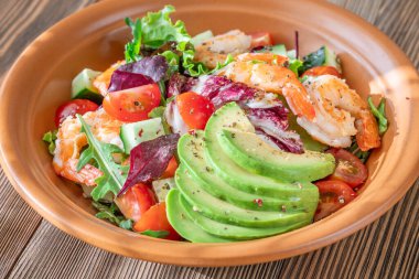 Canlı salata karidesleri avokado taze yeşiller narenciye soslu ahşap masa kırsalları.