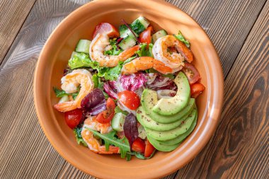 Canlı salata karidesleri avokado taze yeşiller narenciye soslu ahşap masa kırsalları.