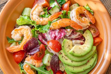 Canlı salata karidesleri avokado taze yeşiller narenciye soslu ahşap masa kırsalları.