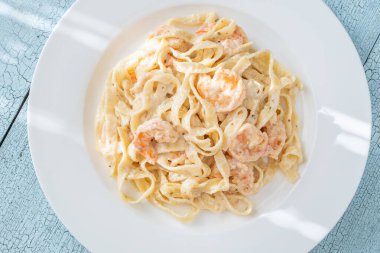 Karidesli kremalı makarna yumuşak erişteler beyaz tabak taze otlar.