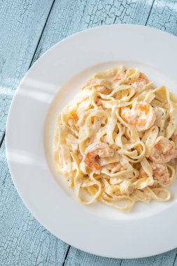 Karidesli kremalı makarna yumuşak erişteler beyaz tabak taze otlar.