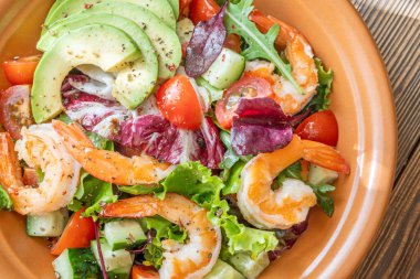 Canlı salata karidesleri avokado taze yeşiller narenciye soslu ahşap masa kırsalları.