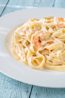 Karidesli kremalı makarna yumuşak erişteler beyaz tabak taze otlar.