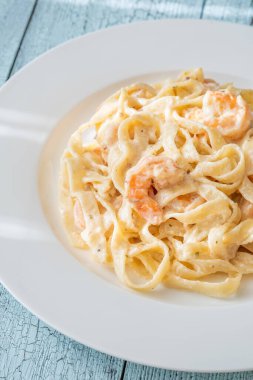 Karidesli kremalı makarna yumuşak erişteler beyaz tabak taze otlar.