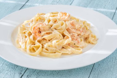 Karidesli kremalı makarna yumuşak erişteler beyaz tabak taze otlar.