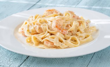 Karidesli kremalı makarna yumuşak erişteler beyaz tabak taze otlar.