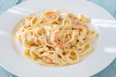 Karidesli kremalı makarna yumuşak erişteler beyaz tabak taze otlar.